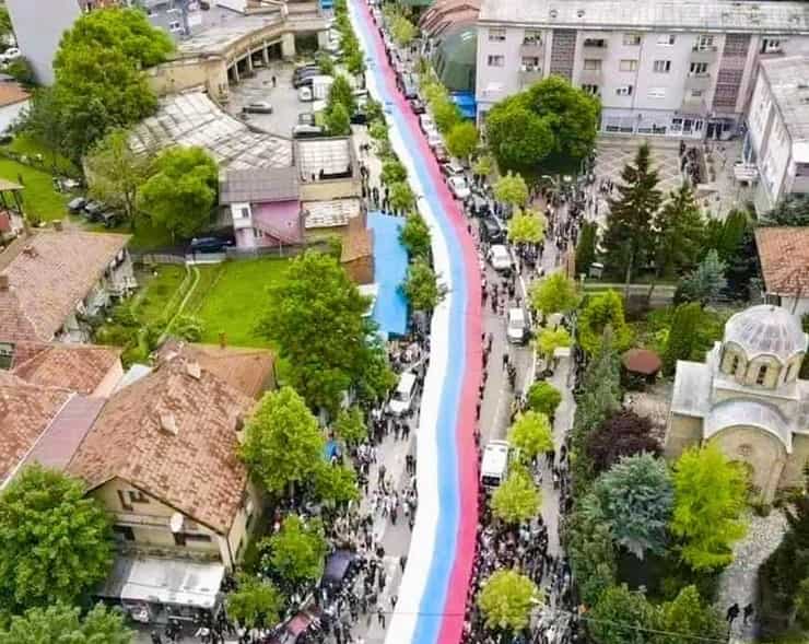 Manifestanti srotolano un’enorme bandiera serba a Zvečan, Kosovo, nel maggio 2023