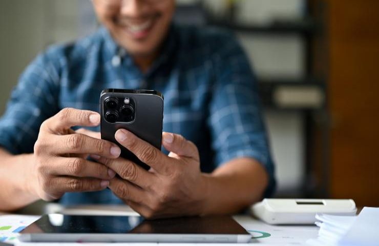 Un uomo con sguardo felice utilizza il suo smartphone ecco perché - fonte SiciliaNews24.it Corporate+ - RomaIt.it